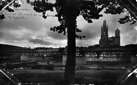 Vista del riu Onyar a l'altura del pont del Ferrocarril, en segon terme. A l'esquerra, la palanca del carrer del portal de la Barca. Al fons sobresurten el campanar de l'Esgl&eacute;sia de Sant Feliu i la Catedral de Girona. 1920-1930