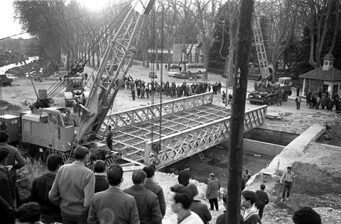 Obres de desmuntatge i trasllat del pont del Rellotge, sobre el riu G&uuml;ell. Grues aixecant l'estructura en l'empla&ccedil;ament original a la Devesa, al costat de la Casa del Rellotge. Mar&ccedil; 1963