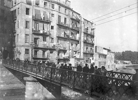 Gent creuant el pont de Sant Agust&iacute;, sobre el riu Onyar. Al fons, a la dreta, el pont d'en G&oacute;mez i el pont del Ferrocarril. 1915-1920