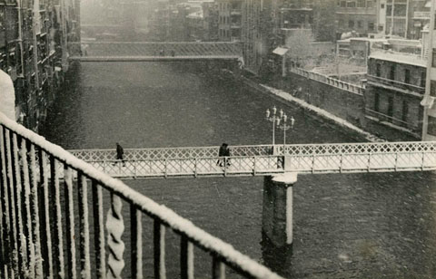 Vista del riu Onyar i les cases del riu despr&eacute;s d'una nevada. En primer terme el pont de Sant Agust&iacute;, que va ser substitu&iuml;t per un de nou el 1973. Al fons el pont de les Peixateries Velles. 1960-1970