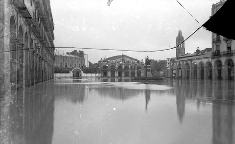Pla&ccedil;a de Sant Agust&iacute; inundada. Nom&eacute;s sobresurt el monument als Defensors de Girona. Al fons es veuen els cinemes Coliseu i Alb&eacute;niz. 1940