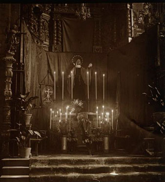 Vista parcial d'un altar ornamentat per la celebraci&oacute; de la Setmana Santa a l'esgl&eacute;sia de Sant Feliu. A la dreta de la imatge s'observen dues dones resant. 29 de mar&ccedil; 1923