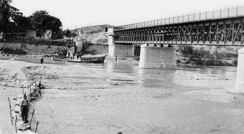 Vista del riu Ter a l'altura del Pont de la Barca, en fase de construcci&oacute;. Sota el pont, la barca que d&oacute;na nom al pont. 1902