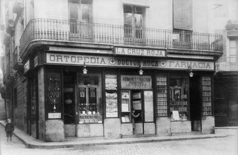 Establiment Ortop&egrave;dia-farm&agrave;cia Doctor Roca a la pla&ccedil;a de l'Oli. Fa&ccedil;ana de l'establiment on apareix el r&egrave;tol de la farm&agrave;cia i el de l'administraci&oacute; de loteria n� 2. 1935-1940
