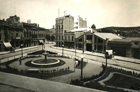 La pla&ccedil;a del Marqu&egrave;s de Camps. Al centre, el garatge Internacional, a l'esquerra, l'establiment d'alimentaci&oacute; Busquets. 1925-1930