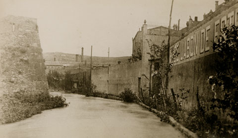 A l'esquerra, el baluard del Governador; a la dreta, la f&agrave;brica de Sab&oacute; Esteve Bachs i la s&egrave;quia Monar, posteriorment coberta pel carrer del mateix nom. . 1900