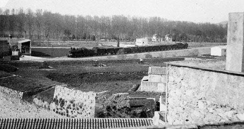 Vista de la Devesa des del baluard de la Santa Creu. En primer terme, les restes del baluard. En segon terme, un tren circulant pel terrapl&egrave; del tren a l'altura del carrer Bonastruc. 1903
