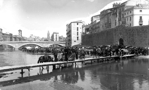 El mercat del bestiar a l'Areny, davant el tram de muralla del Pes de la Palla. Al centre, la palanca d'en Vila, que salvava el riu Onyar i comunicava el portal de l'&Agrave;ngel, a la dreta, amb l'altre banda del riu. 1880-1890
