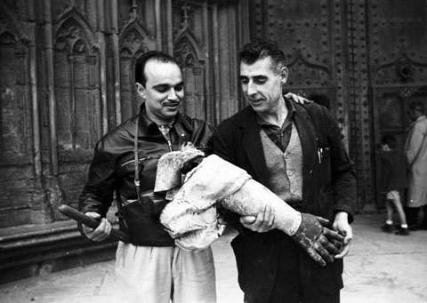 Desmuntatge de l'&Agrave;ngel de la Catedral. Retrat del fot&ograve;graf Josep Buil Mayral amb un dels cosins Rueda davant la porta dels Ap&ograve;stols amb un dels bra&ccedil;os de l'&agrave;ngel retirat. 1960