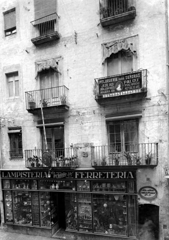 Fa&ccedil;ana d'un edifici a l'Argenteria, on s'observa  l'aparador de la lampisteria-ferreteria 'Casa Priante', a la planta baixa. En un dels balcons hi ha el r&egrave;tol de la perruqueria de dones 'Julio Palou'. 1933