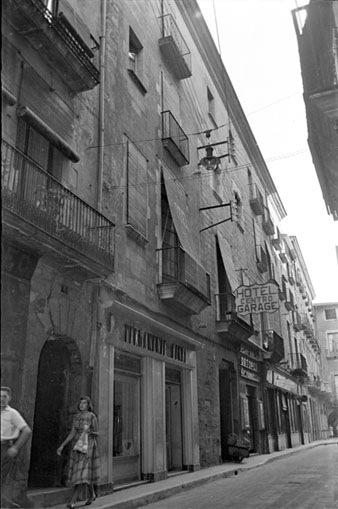 El carrer Ciutadans amb r&egrave;tols comercials: Permanente Henri, Perfumeria Torrellas, al mig Hotel Centro. 1957