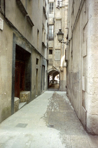 El carrer de les Olles a l'encreuament amb Mercaders. Al fons, el carrer de les Ferreries Velles i la volta d'acc&eacute;s a la Rambla de la Llibertat. L'edifici de la dreta va ser enderrocat per obrir-hi una pla&ccedil;a. 1986