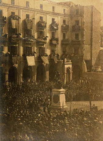 Inauguraci&oacute; del monument als defensors de Girona. Les autoritats encap&ccedil;alades pel Capit&agrave; General de Catalunya Valeri&agrave; Weyler Nicolau i l'alcalde Francesc de Ciurana Hern&aacute;ndez. Darrera l'escultura s'observa l'arc construit per l'ocasi&oacute;. Els balcons estan decorats amb domassos. 1894