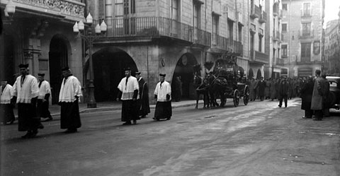 Seguici f&uacute;nebre d'un enterrament al seu pas per la pla&ccedil;a del Vi. Al centre, el carruatge f&uacute;nebre tirat per cavalls engalanats. 1920