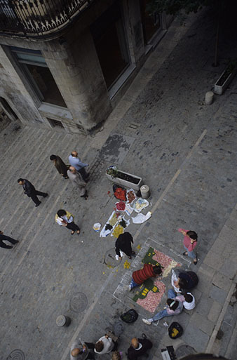 Vista des d'un punt elevat de la pla&ccedil;a del Correu Vell amb un grup de gent fent una catifa de Corpus. 1990