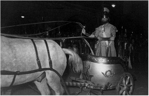 La biga a la desfilada del X&egrave; aniversari, el Dimecres Sant de l�any 1950, a la pla&ccedil;a del Vi, amb l�auriga Ricard Fina arriant els cavalls per emprendre la pujada del Pont de Pedra