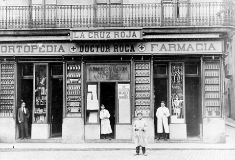 Establiment Ortop&egrave;dia-farm&agrave;cia Doctor Roca. A la fa&ccedil;ana de l'establiment hi apareix el r&egrave;tol de la farm&agrave;cia i el de l'administraci&oacute; de loteria n� 2