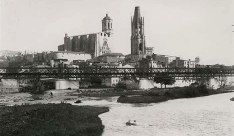 Punt de conflu&egrave;ncia entre els rius Ter i Onyar. A la part central, el pont del Ferrocarril. Al fons, la Catedral de Girona i el campanar de l'esgl&eacute;sia de Sant Feliu. A la dreta, la passarel&middot;la del Portal de la Barca. 1880-1905
