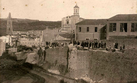 Enderrocament de la muralla del Mercadal a la zona de la Gran Via, a l'altura del baluard de la Santa Creu. En primer terme a la dreta, les naus de la f&agrave;brica Gr&ograve;ber. Al fons d'esquerra a dreta, la muntanya de Montju&iuml;c amb el castell, el campanar de l'esgl&eacute;sia de Sant Feliu i la Catedral de Girona. 1901-1908