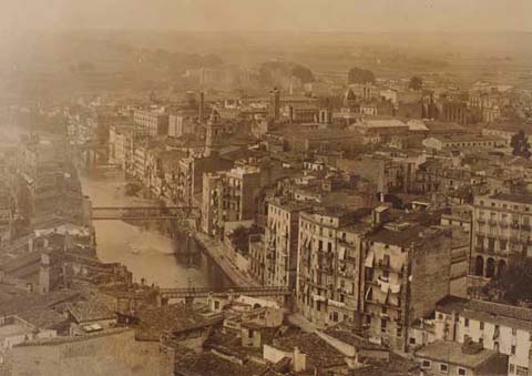Vista a&egrave;ria del Mercadal, amb el campanar de les Bernardes, la torre de la Casa de les Aig&uuml;es, el campanar de l'esgl&eacute;sia de Santa Susanna i la c&uacute;pula de la f&agrave;brica Grober. 1910-1926